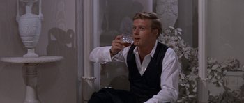 Movie still from “Inside Daisy Clover” (1965), directed by Robert Mulligan – A man sitting down holding a glass of wine; Medium shot, Over the shoulder angle