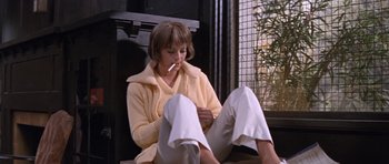 Movie still from “Inside Daisy Clover” (1965), directed by Robert Mulligan – A woman sitting on the ground with a cigarette in her mouth; Medium shot, Low angle