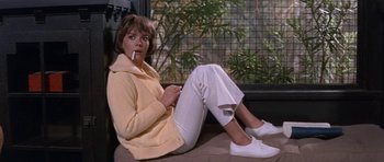 Movie still from “Inside Daisy Clover” (1965), directed by Robert Mulligan – A woman sitting on the ground with a cigarette in her mouth; Medium shot, Low angle