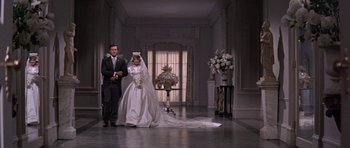 Movie still from “Inside Daisy Clover” (1965), directed by Robert Mulligan – A man and woman in wedding attire walking down a hall way; Wide shot, Low angle