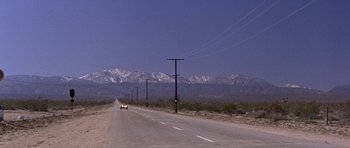 Movie still from “Inside Daisy Clover” (1965), directed by Robert Mulligan – A car driving down a road near a mountain range; Extreme Wide shot, Low angle