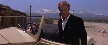 Movie still from “Inside Daisy Clover” (1965), directed by Robert Mulligan – A man in a suit and tie in a car with mountains in the background; Medium shot, Over the shoulder angle
