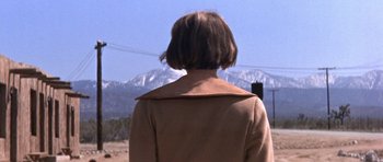 Movie still from “Inside Daisy Clover” (1965), directed by Robert Mulligan – A woman wearing a brown coat standing in front of a mountain range; Close Up shot, Low angle