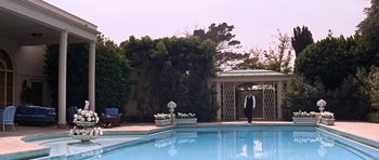 Movie still from “Inside Daisy Clover” (1965), directed by Robert Mulligan – A man standing next to a swimming pool; Extreme Wide shot, Low angle