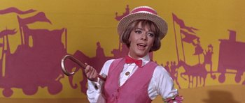 Movie still from “Inside Daisy Clover” (1965), directed by Robert Mulligan – A woman in a pink vest and hat holding a wooden stick; Close Up shot, Low angle