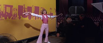 Movie still from “Inside Daisy Clover” (1965), directed by Robert Mulligan – A man in a circus outfit is holding a whip; Wide shot, Low angle