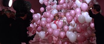 Movie still from “Inside Daisy Clover” (1965), directed by Robert Mulligan – A man dressed as a clown surrounded by pink and white balloons; Wide shot, High angle