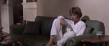 Movie still from “Inside Daisy Clover” (1965), directed by Robert Mulligan – A woman sitting on a green couch holding a remote control; Medium shot, High angle