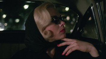 Movie still from “Insignificance” (1985), directed by Nicolas Roeg – A woman with red nails and sunglasses in a car at night; Close Up shot, Over the shoulder angle