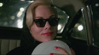 Movie still from “Insignificance” (1985), directed by Nicolas Roeg – A woman holding a frisbee in a car; Close Up shot, High angle