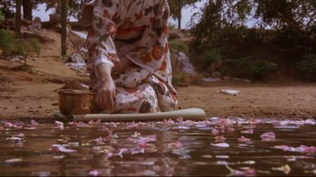 Movie still from “Insignificance” (1985), directed by Nicolas Roeg – A woman in a kimono sitting on the ground near a body of water; Wide shot, High angle