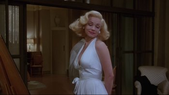 Movie still from “Insignificance” (1985), directed by Nicolas Roeg – A woman in a white dress standing next to a door way; Medium shot, Low angle