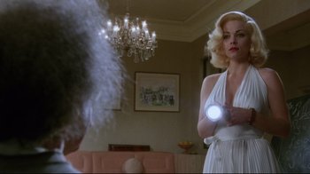 Movie still from “Insignificance” (1985), directed by Nicolas Roeg – A woman in a white dress is holding a light; Medium shot, Over the shoulder angle