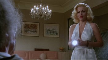 Movie still from “Insignificance” (1985), directed by Nicolas Roeg – A woman holding a nintendo wii game controller in a living room; Medium shot, Low angle