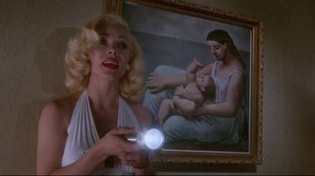 Movie still from “Insignificance” (1985), directed by Nicolas Roeg – A woman holding a flashlight in front of a painting; Medium shot, Low angle