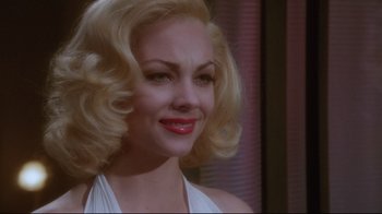 Movie still from “Insignificance” (1985), directed by Nicolas Roeg – A woman with blonde hair and red lipstick; Close Up shot, Over the shoulder angle