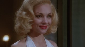 Movie still from “Insignificance” (1985), directed by Nicolas Roeg – A woman with blonde hair wearing a white top; Close Up shot, Over the shoulder angle