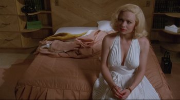 Movie still from “Insignificance” (1985), directed by Nicolas Roeg – A woman sitting on a bed wearing a white dress; Medium shot, High angle