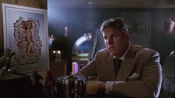 Movie still from “Insignificance” (1985), directed by Nicolas Roeg – A man sitting at a table in a room; Medium shot, Low angle