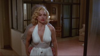 Movie still from “Insignificance” (1985), directed by Nicolas Roeg – A woman in a white dress standing next to a man in a suit; Medium shot, Over the shoulder angle