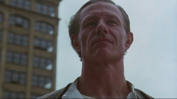 Movie still from “Insignificance” (1985), directed by Nicolas Roeg – A person with a building in the background; Close Up shot, Low angle
