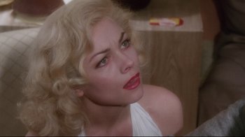 Movie still from “Insignificance” (1985), directed by Nicolas Roeg – A person with blonde hair and red lipstick; Close Up shot, Over the shoulder angle