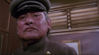 Movie still from “Insignificance” (1985), directed by Nicolas Roeg – An older man wearing a uniform and a hat; Close Up shot, Low angle