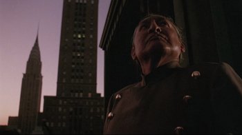 Movie still from “Insignificance” (1985), directed by Nicolas Roeg – A man standing in front of a building at night; Close Up shot, Low angle