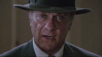Movie still from “Insignificance” (1985), directed by Nicolas Roeg – An older man wearing a suit and a hat; Close Up shot, Low angle