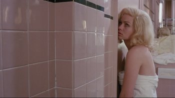Movie still from “Insignificance” (1985), directed by Nicolas Roeg – A woman leaning up against a wall in a bathroom; Medium shot, Low angle