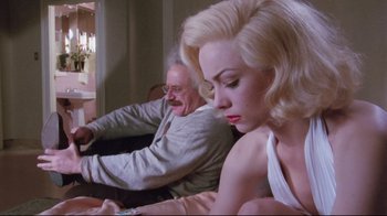 Movie still from “Insignificance” (1985), directed by Nicolas Roeg – An older man and a younger woman sitting on a couch; Medium shot, Low angle