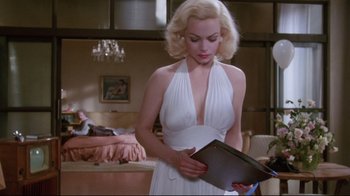 Movie still from “Insignificance” (1985), directed by Nicolas Roeg – A woman in a white dress is holding a book; Medium shot, Low angle