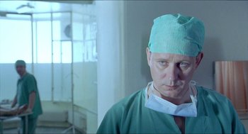 Movie still from “Insomnia” (1997), directed by Erik Skjoldbjærg – A man wearing a green surgical cap and a green gown; Close Up shot, Low angle