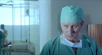 Movie still from “Insomnia” (1997), directed by Erik Skjoldbjærg – A man wearing a surgical mask and a green hat; Close Up shot, Low angle