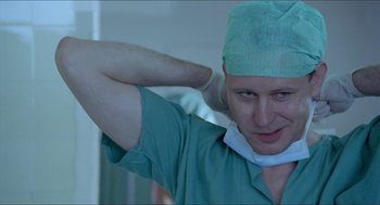 Movie still from “Insomnia” (1997), directed by Erik Skjoldbjærg – A man wearing a green surgical gown and a green surgical cap; Close Up shot, Low angle