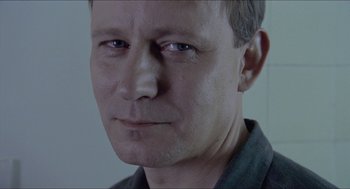 Movie still from “Insomnia” (1997), directed by Erik Skjoldbjærg – A man's face in a room; Close Up shot, Over the shoulder angle