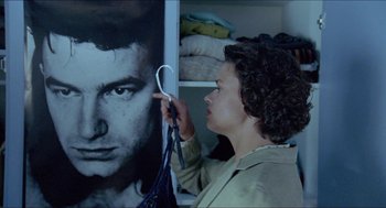 Movie still from “Insomnia” (1997), directed by Erik Skjoldbjærg – A woman is holding a pair of scissors in front of a picture of a man; Close Up shot, Over the shoulder angle