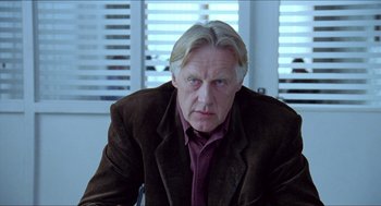 Movie still from “Insomnia” (1997), directed by Erik Skjoldbjærg – An older man wearing a brown jacket and purple shirt; Close Up shot, Low angle
