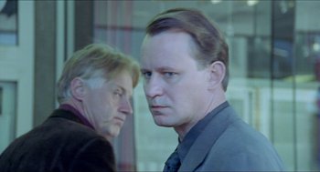 Movie still from “Insomnia” (1997), directed by Erik Skjoldbjærg – Two men standing next to each other in front of a window; Close Up shot, Over the shoulder angle