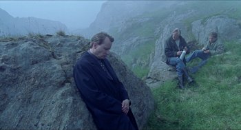 Movie still from “Insomnia” (1997), directed by Erik Skjoldbjærg – A man sitting on top of a rock next to another man; Wide shot, High angle