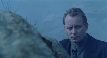 Movie still from “Insomnia” (1997), directed by Erik Skjoldbjærg – A man standing next to a tree stump; Close Up shot, Low angle
