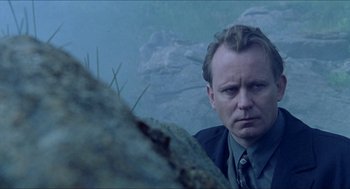 Movie still from “Insomnia” (1997), directed by Erik Skjoldbjærg – A man standing in front of some rocks; Close Up shot, Low angle