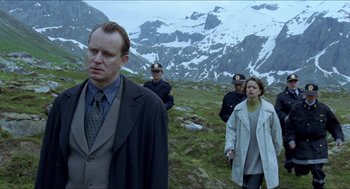 Movie still from “Insomnia” (1997), directed by Erik Skjoldbjærg – A group of people standing on top of a grass covered hill; Medium shot, Low angle