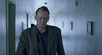 Movie still from “Insomnia” (1997), directed by Erik Skjoldbjærg – A man wearing a suit and tie in a hallway; Medium shot, Low angle