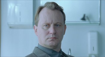 Movie still from “Insomnia” (1997), directed by Erik Skjoldbjærg – A person wearing a suit and tie; Close Up shot, Low angle