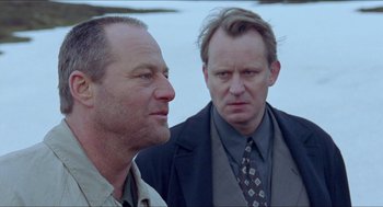 Movie still from “Insomnia” (1997), directed by Erik Skjoldbjærg – Two men standing next to each other in front of a body of water; Close Up shot, Low angle