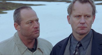 Movie still from “Insomnia” (1997), directed by Erik Skjoldbjærg – Two men standing next to each other near a body of water; Close Up shot, Low angle