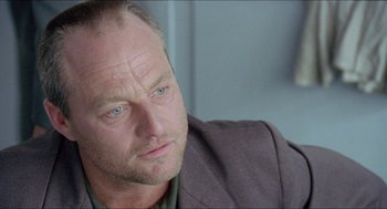Movie still from “Insomnia” (1997), directed by Erik Skjoldbjærg – A person sitting down with his head tilted down; Close Up shot, Low angle