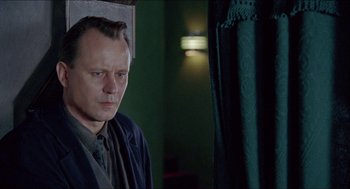 Movie still from “Insomnia” (1997), directed by Erik Skjoldbjærg – A person in a room near a curtain; Close Up shot, Low angle