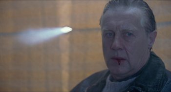 Movie still from “Insomnia” (1997), directed by Erik Skjoldbjærg – An older man with a white beard and blue eyes looking at the camera; Close Up shot, Over the shoulder angle